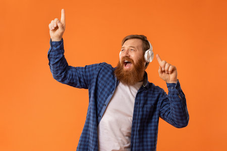 Portrait of funny guy singing listening music in headphones, studioの写真素材