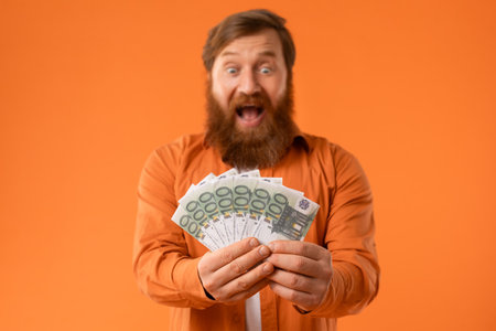 man shouting with happiness holding bundle of Euro cash, studioの写真素材