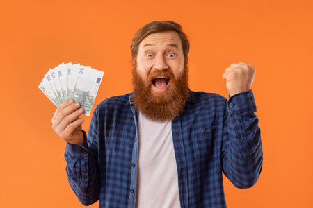 man holding handful of euro banknotes and gesturing yes, studioの写真素材