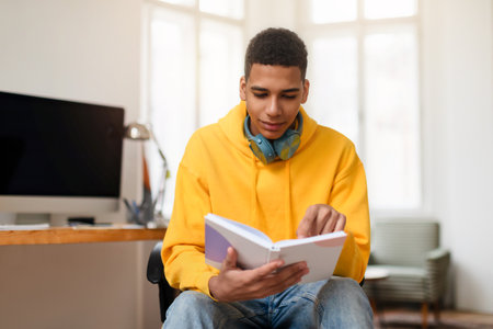 Young man reading a notebook at a home office deskの写真素材