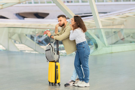 Couple with suitcase at a modern station, late on flightの写真素材