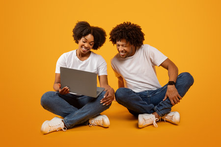 Pretty young black woman showing her husband something on laptop