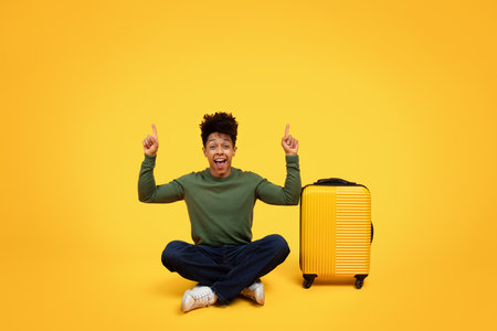 Excited black man sitting with luggageの写真素材