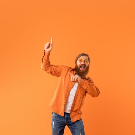 Energetic redhaired man pointing upward with joy while dancing, studioの写真素材