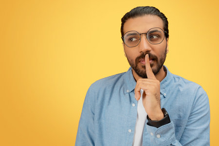 Man with finger on lips in denim shirtの写真素材