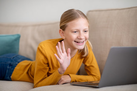 Young Girl Using Laptop on Couch For Video Callの写真素材