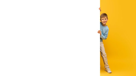 Boy hiding behind a white empty bannerの写真素材