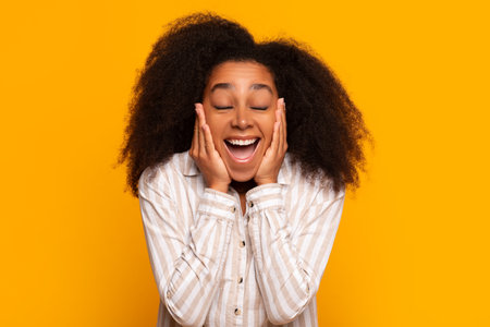 Excited young woman smiling on yellow backgroundの写真素材