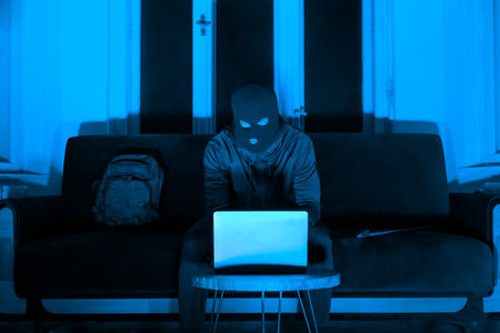 Man on laptop in dark room with blue hueの写真素材