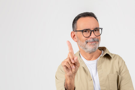 Mature man pointing upwards, smiling, copy spaceの写真素材