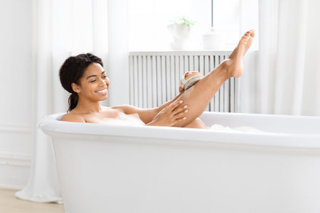 Fun woman scrubbing legs in bubble bathの写真素材
