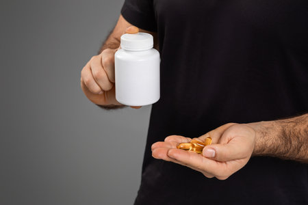 Man holding a bottle and supplements in handの写真素材