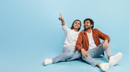 Couple looking and pointing away on blue background