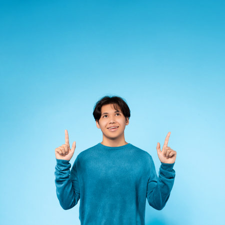 Asian guy looking up with fingers pointing upwardsの写真素材