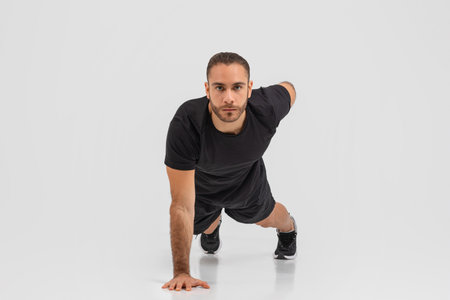 Man in black doing push ups on grey background