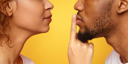 Profile of mysterious woman touching male lips with fingerの写真素材