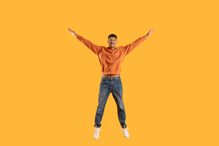 Excited man jumping with joy against yellow background