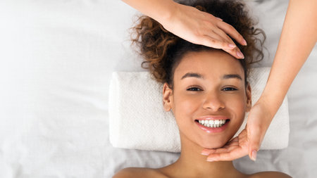 African-american woman enjoying face massage at beauty salonの写真素材