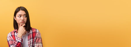 Pensive woman against yellow background, copy spaceの写真素材