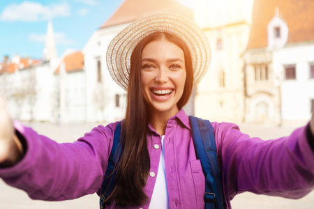 Joyful young woman student takes selfie in city centerの写真素材