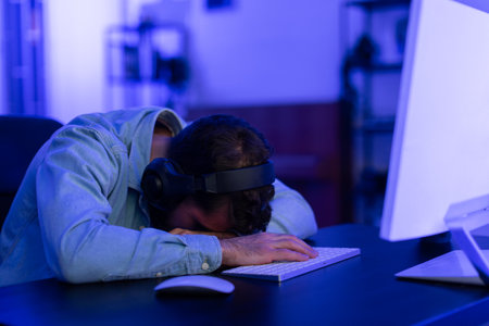 Exhausted gamer asleep on the keyboard at homeの写真素材