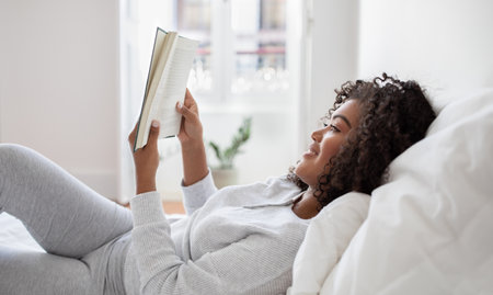 Woman Laying in Bed Reading a Book, Side View