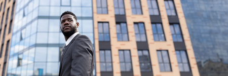 Confident serious african american businessman standing outside modern office building