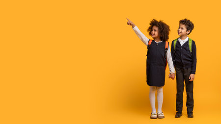 Two Young Students in Uniform Standing Against Yellow, Copy Spaceの写真素材