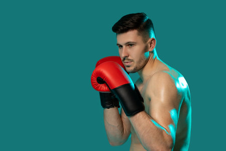 Athletic Man in Boxing Gloves Posing on Green Background, Closeupの写真素材