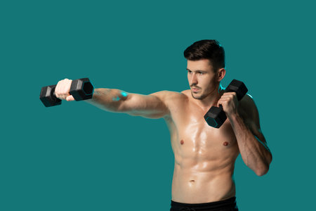 Man Holding Two Dumbbells Against Green Studio Backgroundの写真素材