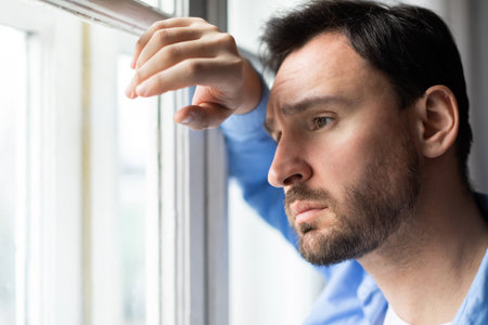 Sad Man Looking Out of a Windowの写真素材