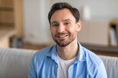 Handsome Bearded Man Smiling on Couch at Homeの写真素材