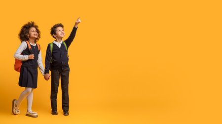 Two Children Schoolers Standing on Yellow Background, Copy Spaceの写真素材