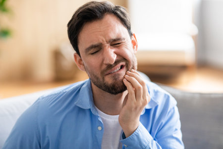 Bearded Man Sitting on Couch With Toothacheの写真素材