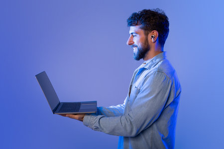 Bearded Man Holding Laptop in Neon Lightの写真素材