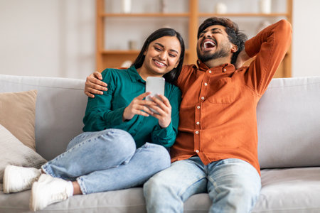 Happy Couple Laughing Together While Looking at Smartphoneの写真素材
