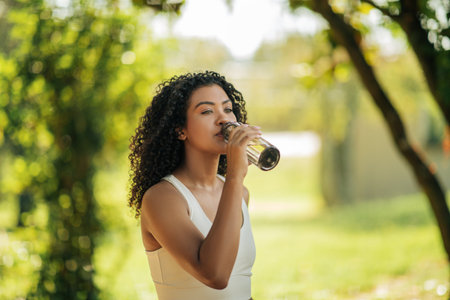 Athletic Woman Drinking From Bottle in Park