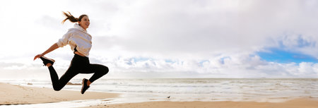 Woman Jumps for Joy on Sandy Beach With Ocean View