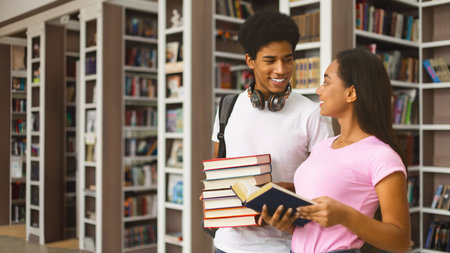 Lovely teenage afro couple discussing book in library