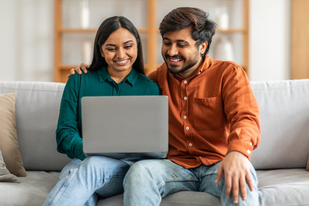Man and Woman Sitting on Couch Looking at Laptop, Scrollingの写真素材