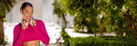 Happy athletic black lady wearing wireless headphones listening to musicの写真素材