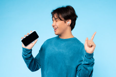 Young Guy Enjoying Music With Wireless Earbuds and Smartphone