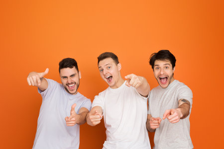 Three smiling guys pointing at the camera