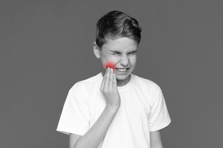 Teen boy touching cheek with painful expressionの写真素材