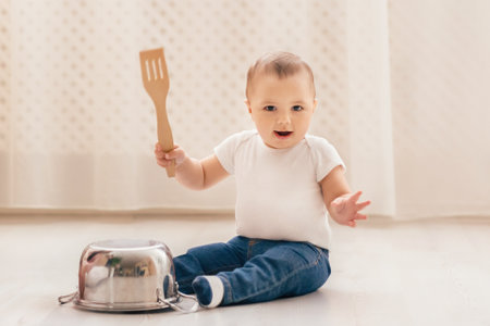 Baby Sitting on the Floor Holding a Spatulaの写真素材