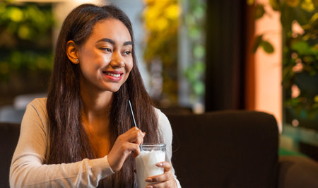 Pretty Young Girl Drinking Glass of Milk in Cafeの写真素材