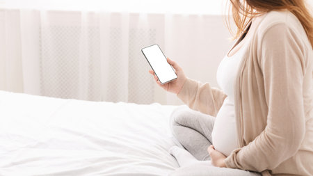 Cheerful millennial pregnant woman browsing on smartphone