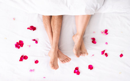 Couples Feet In Bed With Rose Petalsの写真素材