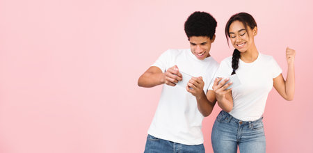 Young Black Guy and Girl Using Cell Phone Against Pink