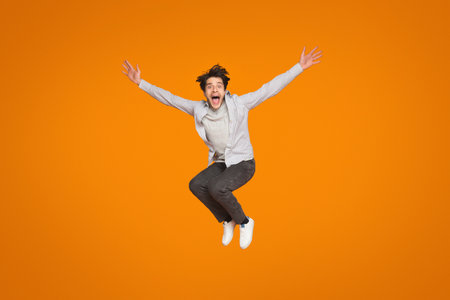 Man jumping with joy on orange backgroundの写真素材